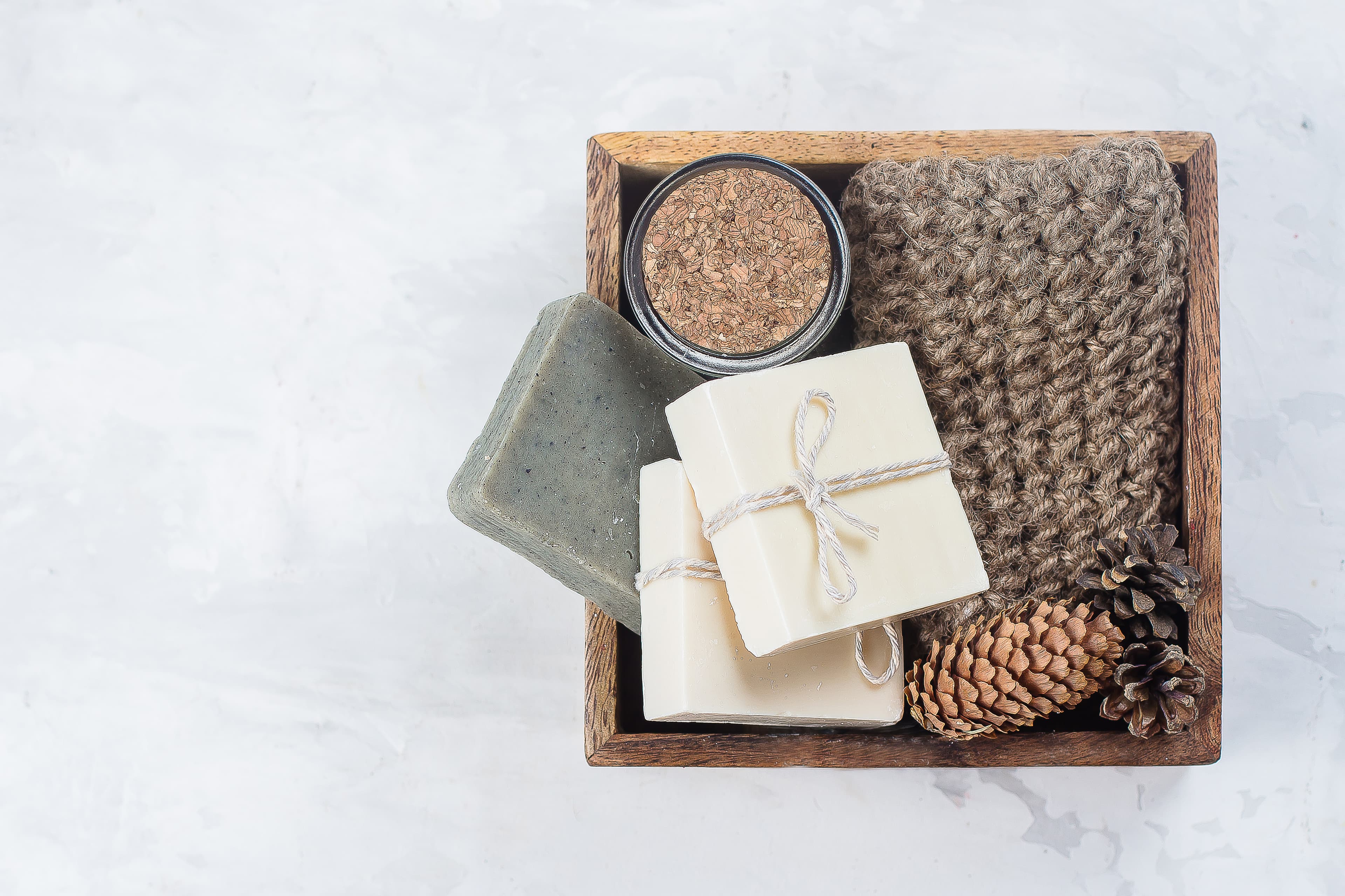 A wooden gift box with wrapped soaps and natural bath accessories