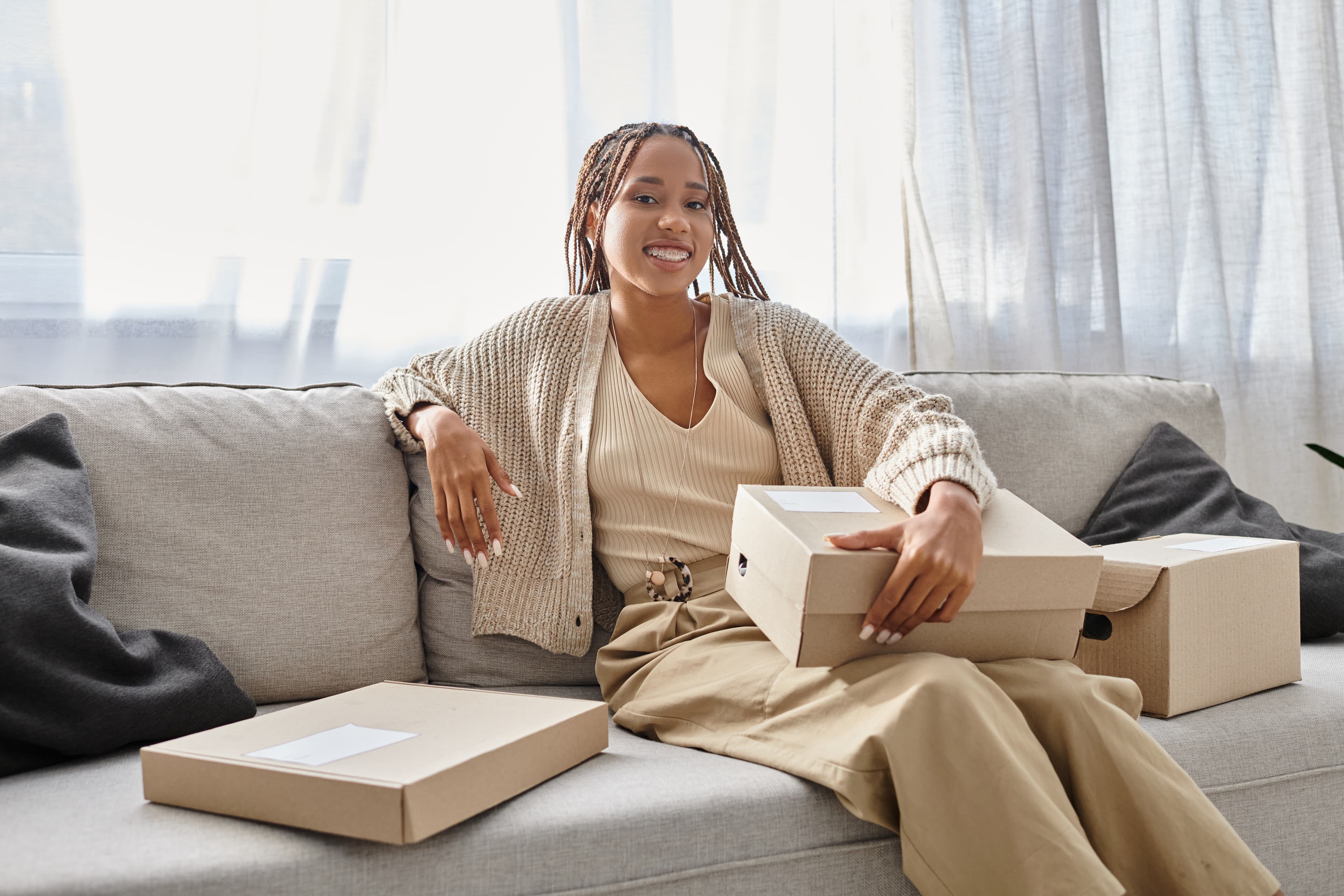 A smiling woman sitting on a couch with gift boxes
